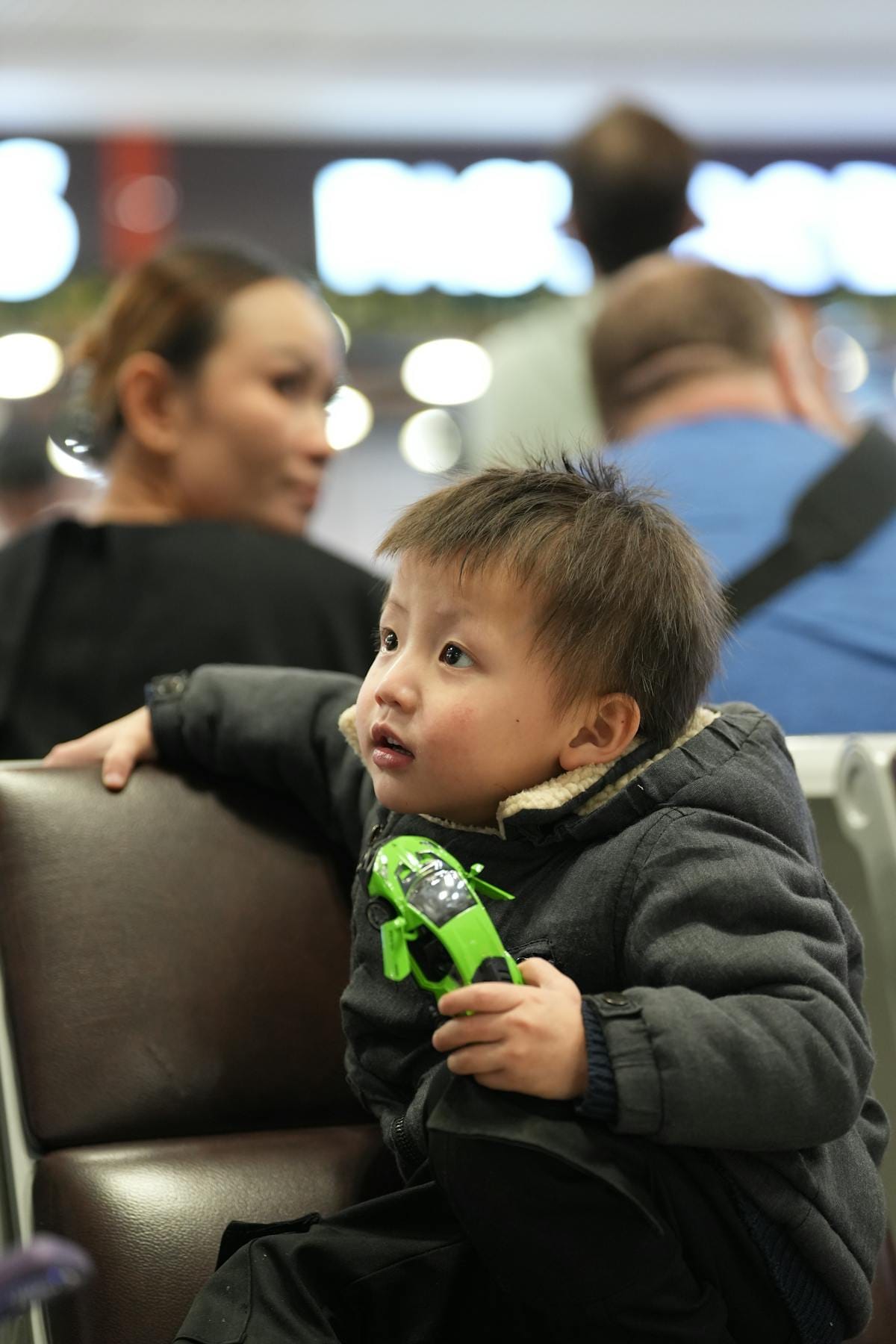 Barn med leksak i flygplatsloungen bland resenärer