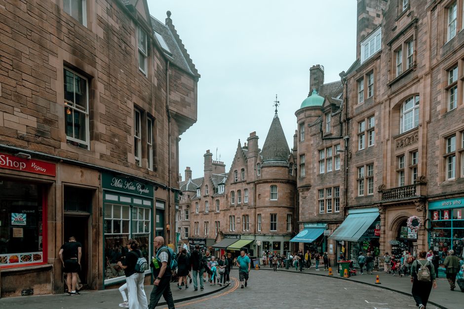 Folkliv på en gata i Edinburghs gamla stad med historiska stenbyggnader längs Royal Mile