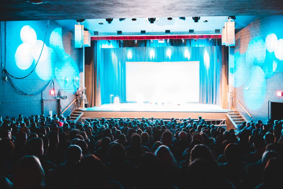 Teaterscen med en fängslad publik under starka strålkastare på en föreställning under festivalen