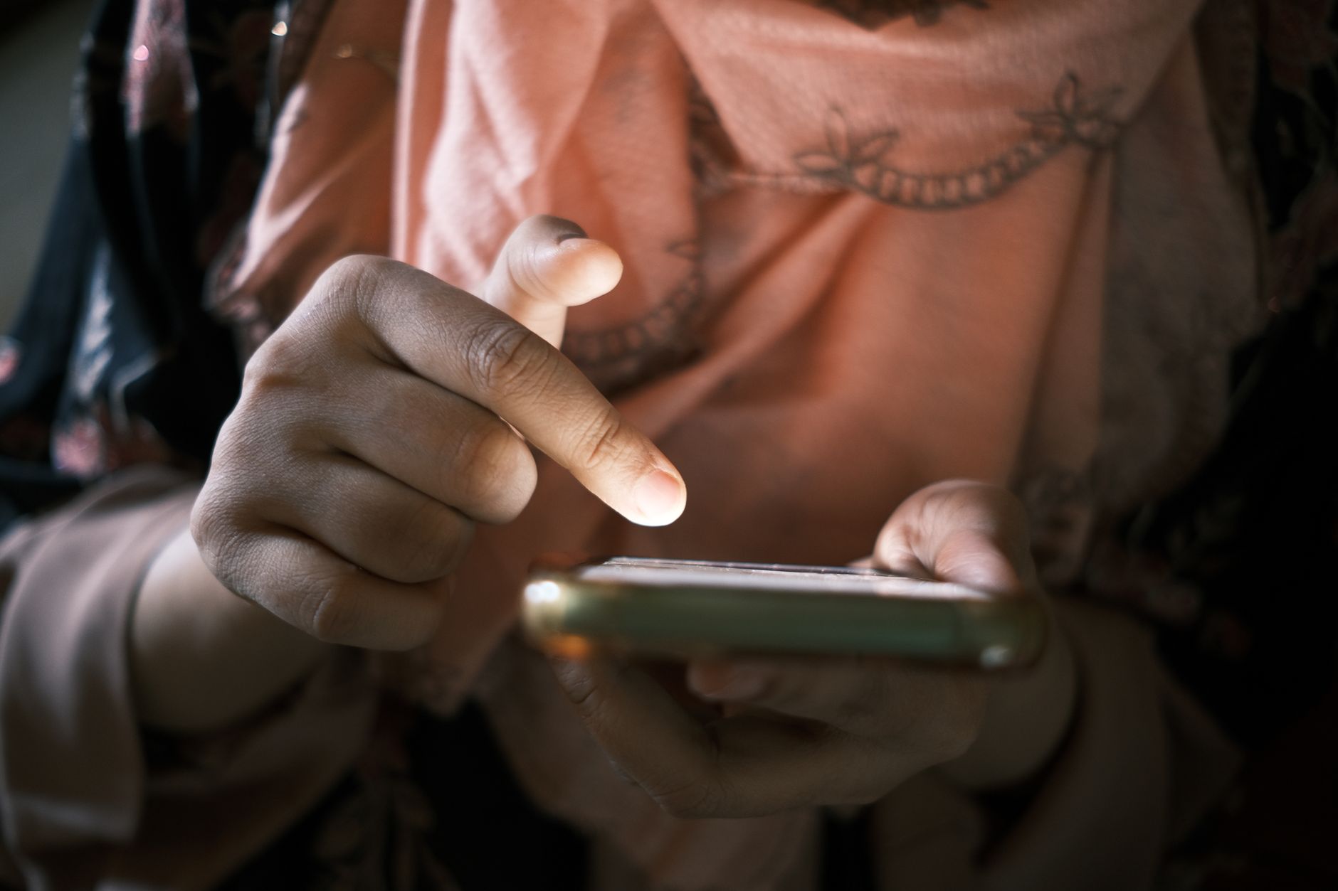 En person fyller i en digital ansökan på sin smartphone vid ett köksbord